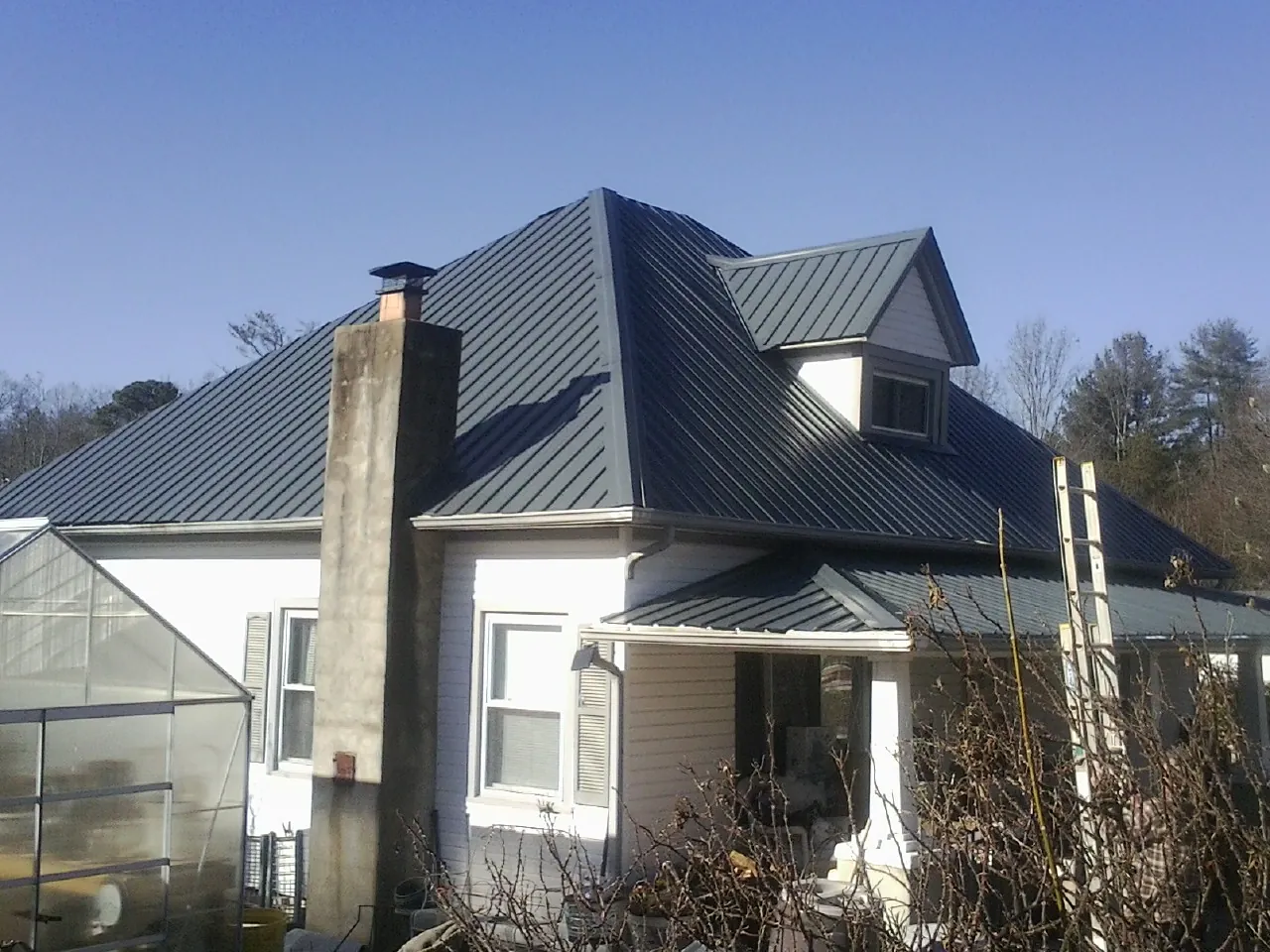 Dark blue standing seam metal roof on a white farmhouse with dormer — Slate & Tile Roof Repair by Roofing Brothers in Green Pond