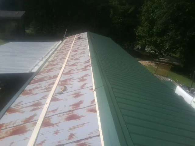 Old rusted panels beside newly installed green metal roofing — Wind Damage Roof Repair by Roofing Brothers in Green Pond