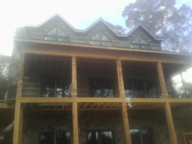Dormers and porch framing on a large log home under construction — Roof Coating work by our crew in Green Pond