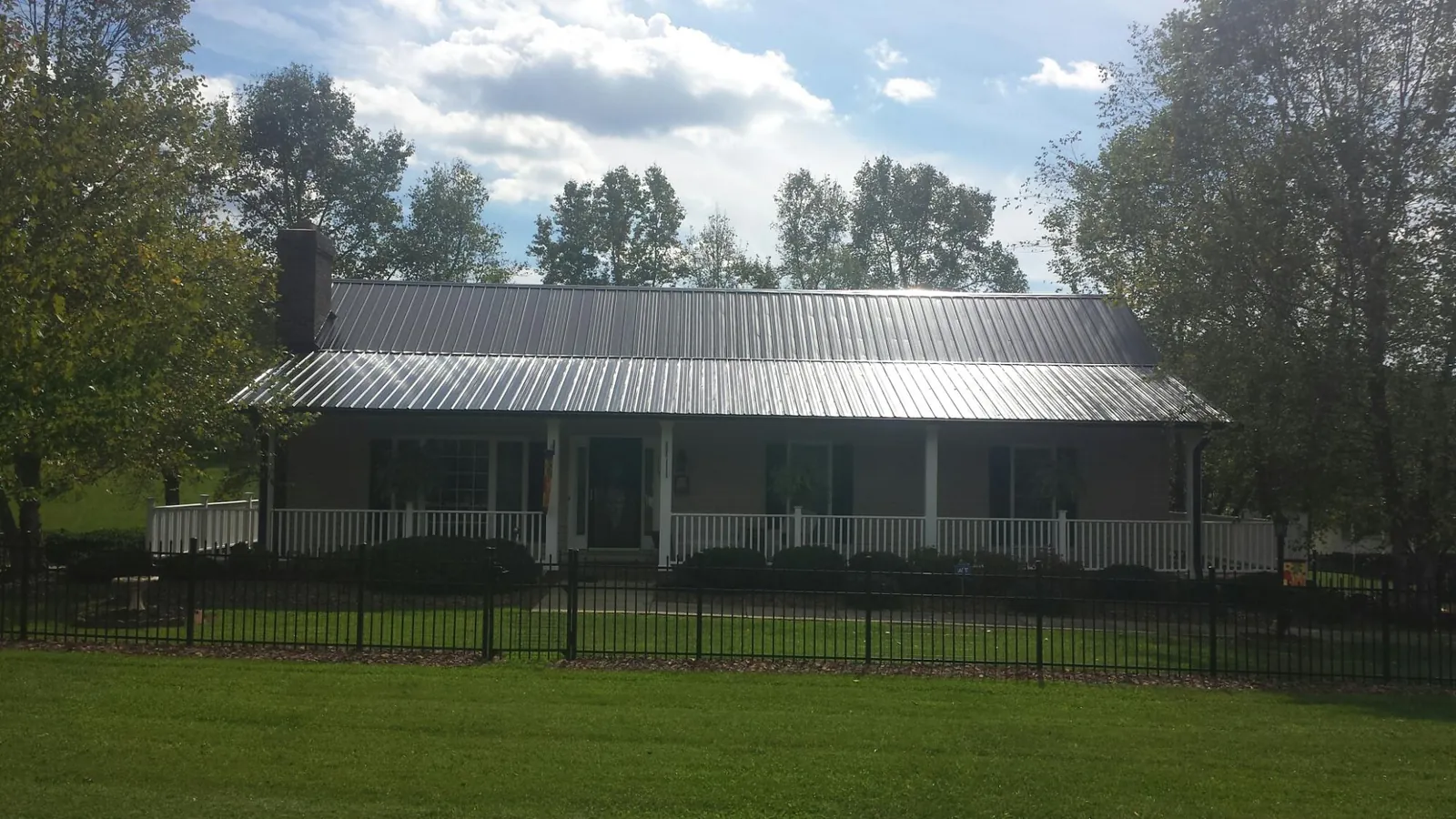 Gray metal roof on a brick ranch with a full width front porch — Gutter Guard Installation work by our crew in Green Pond