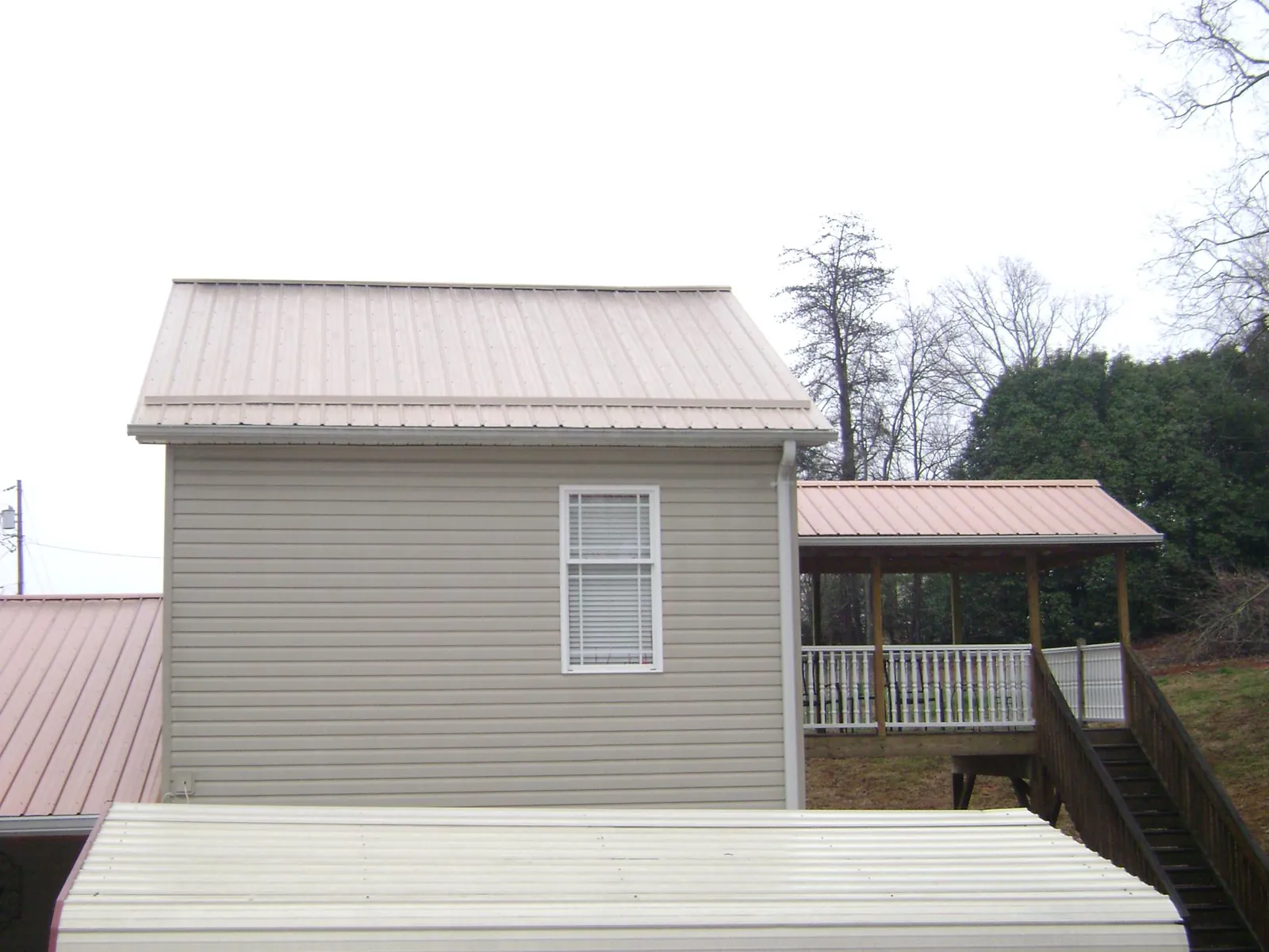 Tan metal roofs on a two story addition and attached porch, from a Roof Replacement job in Green Pond